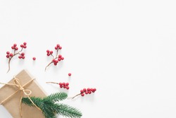 Christmas gift on white background with pine branches, berries and rope. Flat lay, top view, copy space
