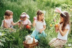 Easter egg hunt. Group Of Children Wearing Bunny Ears Running To Pick Up colorful Egg On Easter Egg Hunt In Garden. Easter tradition. Laughing children in park with basket spring concept