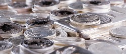 Closeup of Silver bars and silver coins stacked on wooden table
