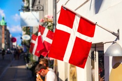 Copenhagen iconic view. Denmark flags near Nyhavn canal on medieval houses in the center of Copenhagen, Denmark during summer sunny day