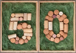 Number 50 fifty  made of wine corks on green background in wooden box