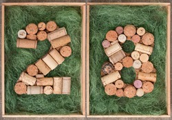 Number 28 twenty eight  made of wine corks on green background in wooden box