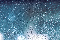 Close up of rain drops on the window in rainy night, cool lights