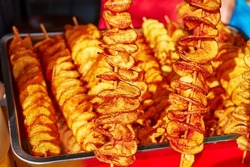 potatoes cut into a spiral and fried. tornado potato. street food. close-up photo
