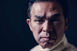 Middle-aged Asian man in white turtleneck wool sweater under black background. Concept image of Warm Biz, stability in daily life, and sustainable living.