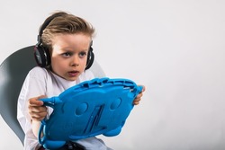 Portrait of young scary boy in headphones and  holding a tablet 