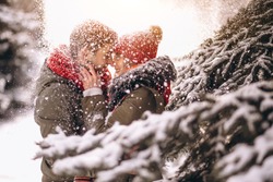 Couple in winter by the fir tree under falling snow