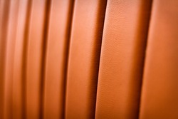 Texture of an expensive leather sofa in close-up with a blurred background. Textured pattern of a sofa made of a material that imitates leather. Orange leatherette material. Abstract screensaver.