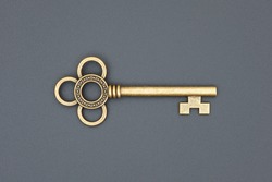 old ornate golden decorative key, vintage design element, isolated object, close-up, top view, flat lay on the black grungy background