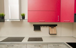 modern loft-style kitchen with red cabinets, stove, range hood and table with countertop.