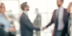blurry image of a handshake of business people at a meeting in the office.