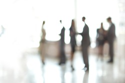 blurry image of a group of business people standing in the office lobby.