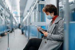 young woman with a digital tablet sitting in an empty subway car.