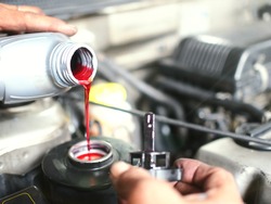 The auto mechanic is refilling additional brake fluid after the inspection and repair of the damaged parts.