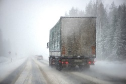 Blurred background of a moving truck on a highway in winter. Freight transport, transportation of goods.