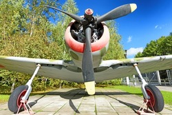 vintage prop driven engine military fighter aircraft in camouflage front view with airplane parts nose fuselage propeller detail exterior panoramic wide transportation war patriotic theme scene
