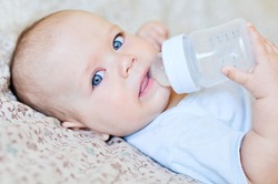 baby holding bottle and drinking water