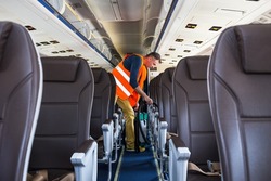 Aircraft cleaning service. Man cleaner working in airplane salon