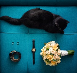 Different lifestyle accessories lie on the table such as: belt, ring, watches,wedding bouquet and cat