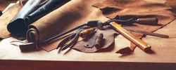 Shoemaker's work desk. Tools and leather at cobbler workplace. Set of leather craft tools on wooden background. Shoes maker tools on wooden table