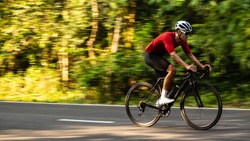 side view of Asian man in red cycling jersey on road bike. Speed, Competition, movement motion.