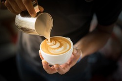 Hand on Barista making latte cafe, Cup of coffee with beautiful Latte art on white cup