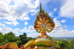 Wat Tham Pha Daen ฺBig buddha statue and naga snake in wat tham pha dean on blue sky background, beautiful buddha statue in sakon nakhon, Thailand for buddhist people spiritual and tourism travel. 