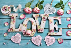 sea blue wooden background with vintage style letters forming word LOVE and roses