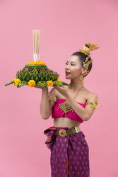 Loy Krathong Festival;woman in thai traditional outfit holding decorated buoyant 