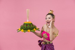 Loy Krathong Festival;woman in thai traditional outfit holding decorated buoyant 