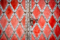 Beautiful ornate church door with a checkered pattern, red-gray color. Roman Catholic parish church. Pseudo-Gothic style.