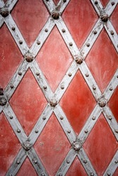 Beautiful ornate church door with a checkered pattern, red-gray color. Roman Catholic parish church. Pseudo-Gothic style.