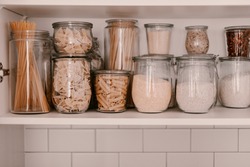 Kitchen storage organization. Zero waste, plastic free. Pasta, grains in glass jars. Organic food. Home cooking. Pantry food cabinet. Nutrition food. Glass containers. Food preparation. Stay home.