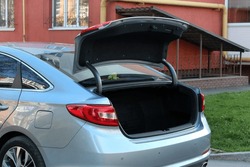 Grey Car with open trunk. Modern car with open empty trunk outdoors.