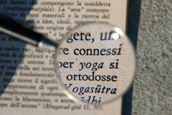 Yoga concept: words from a book written in Italian enlarged by a magnifying glass
