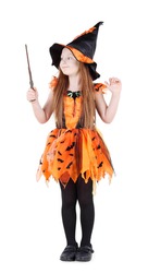 Little girl in orange costume of witch for Halloween holds and looks at wand isolated on white background.