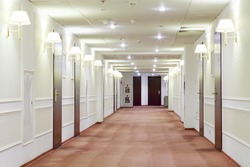 Spacious light hallway with many doors leading into hotel rooms.
