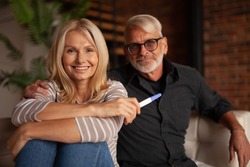 Happy mature husband and wife with pregnancy test. The older family is planning a child.