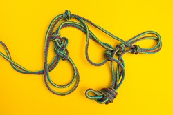 A tangled skein of rope with knots on a yellow background.