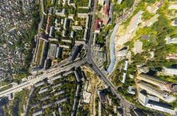 Aerial city view with crossroads and roads, houses, buildings, parks and parking lots, bridges. Copter shot. Panoramic image.