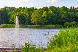 Natural beautiful panorama view with lake river fountain walking pathway and green plants trees in the forest of Speckenbütteler Park in Lehe Bremerhaven Germany.