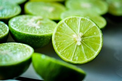 lime Backgrounds, Close up shot, fruit macro photography, Close up sliced of the green limes and seed with a knife place on plastic board in a kitchen. Lime is a kind of fruit. The result is very sour