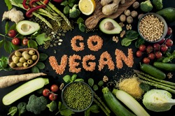 Go vegan concept with lettering. variety of fresh green organic vegetables & lentils on dark background. Vegan food concept.