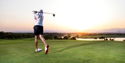 Professinal golf player on golf course. Pro golfer taking a shot at the sunset