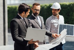 Hipster business man and Office building owner and energy engineer plan a project to build a solar panel for the building under construction. clean and green alternative energy concept.