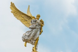 Winged gilded goddess in silver and gold holding cornucopia, a symbol of abundance and plenty.