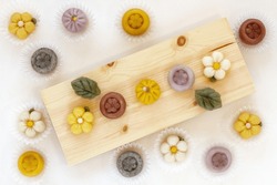 Traditional Korean rice cakes 'Jeolpyeon' made in various shapes on wooden dish. Holiday food. Top view.
