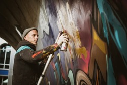 Graffiti artist painting with aerosol spray on the wall