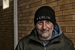 Portrait of homeless man in front of tiled wall