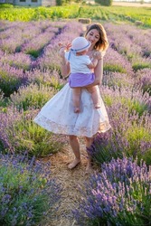 woman with daughter on lavender field happy dancing at sunrise on warm summer day. 